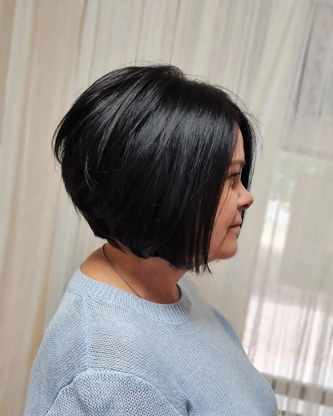 Black angled bob in profile with pale blue sweater