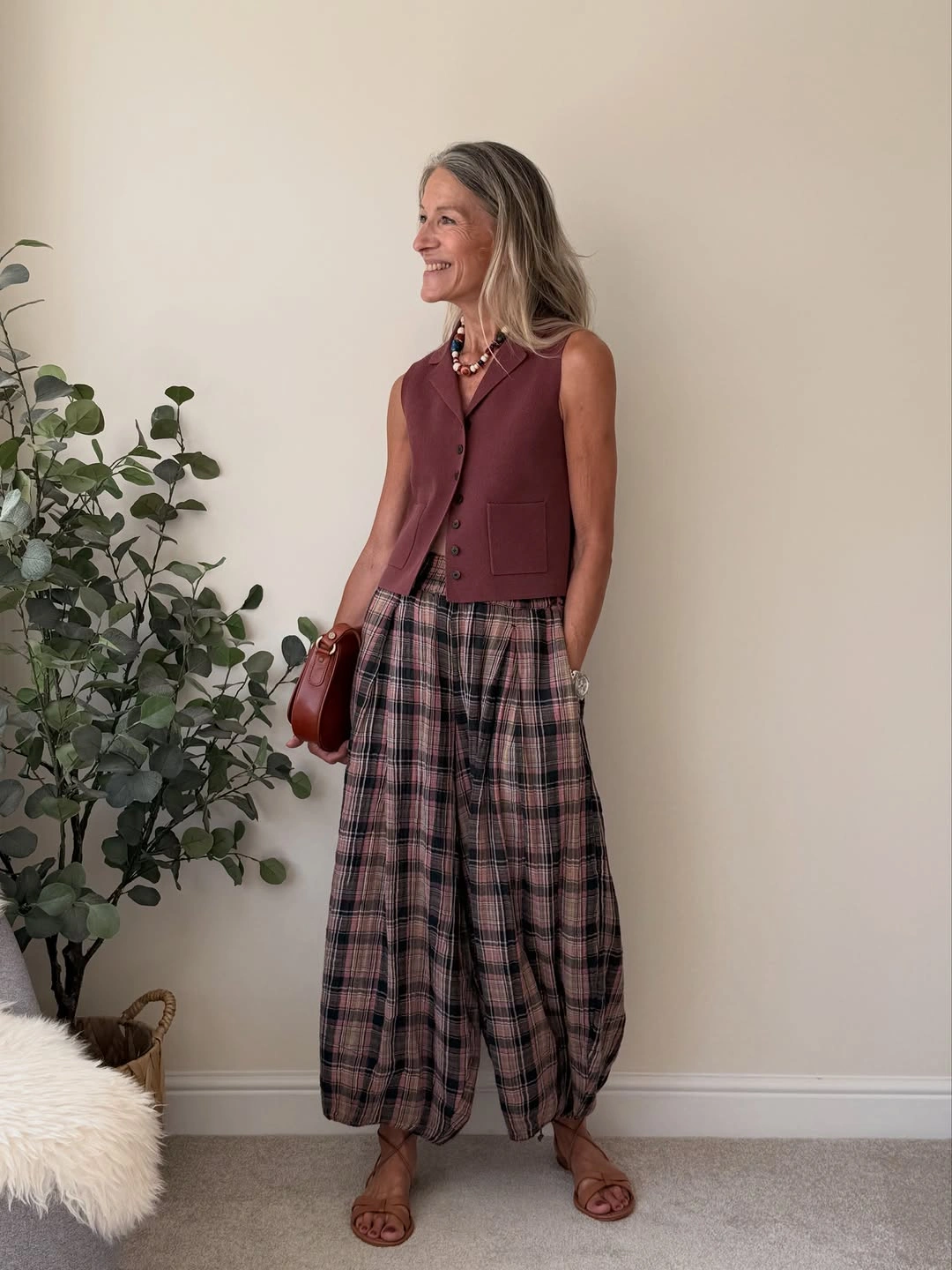 Burgundy vest with plaid balloon trousers and brown bag