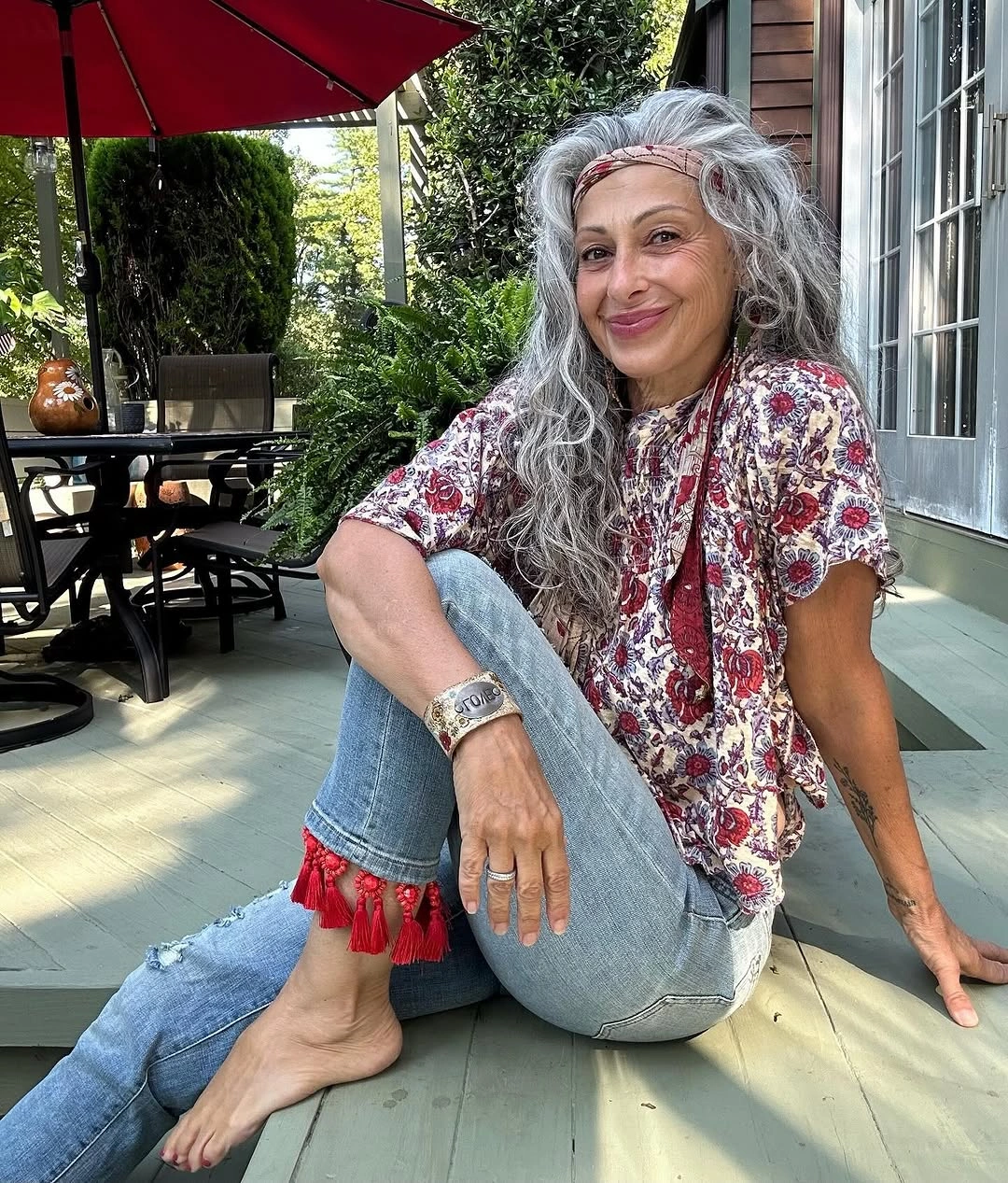 Floral blouse, pale jeans, red tassel cuffs and headband