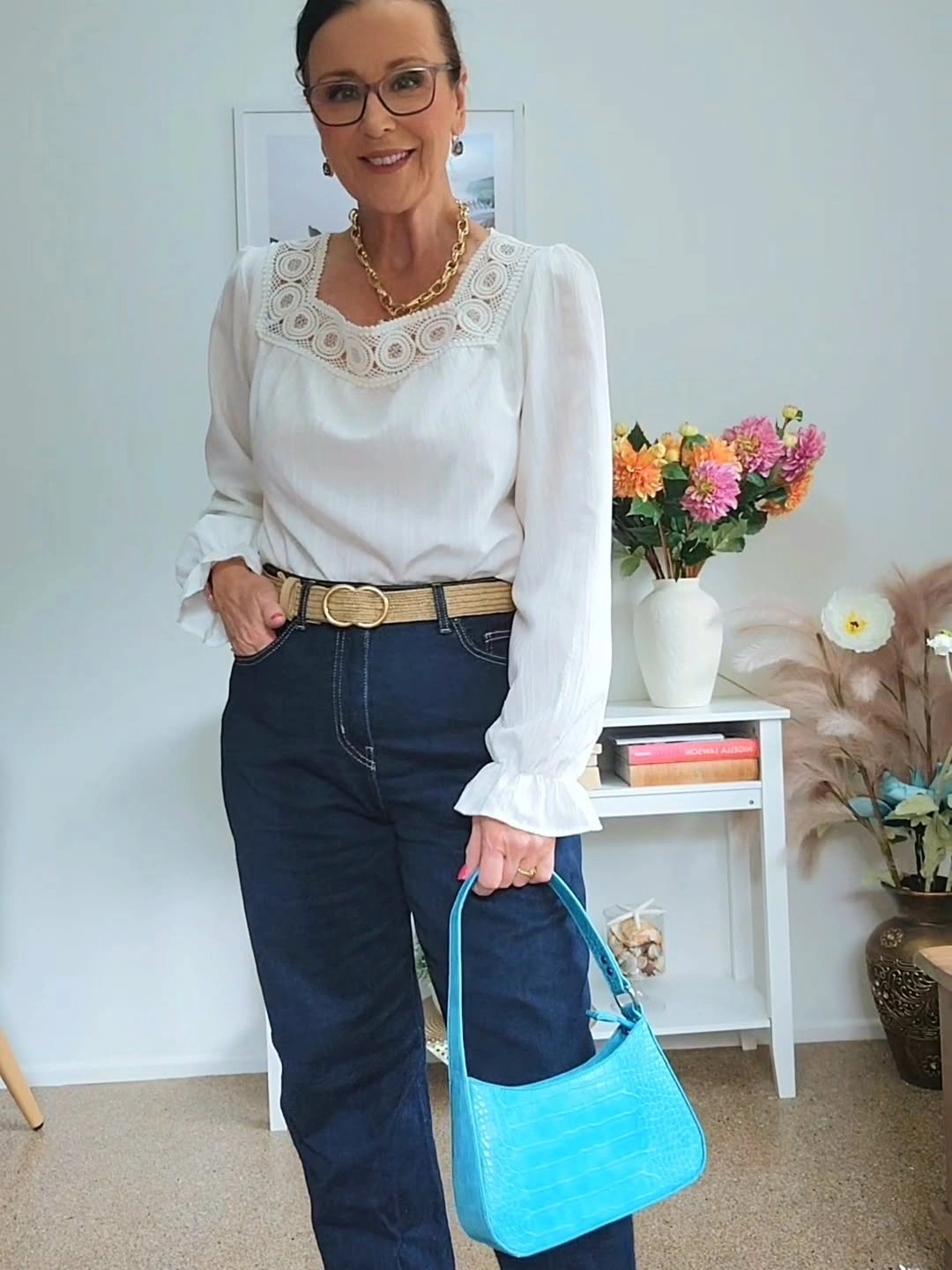 White lace blouse with dark jeans and turquoise handbag