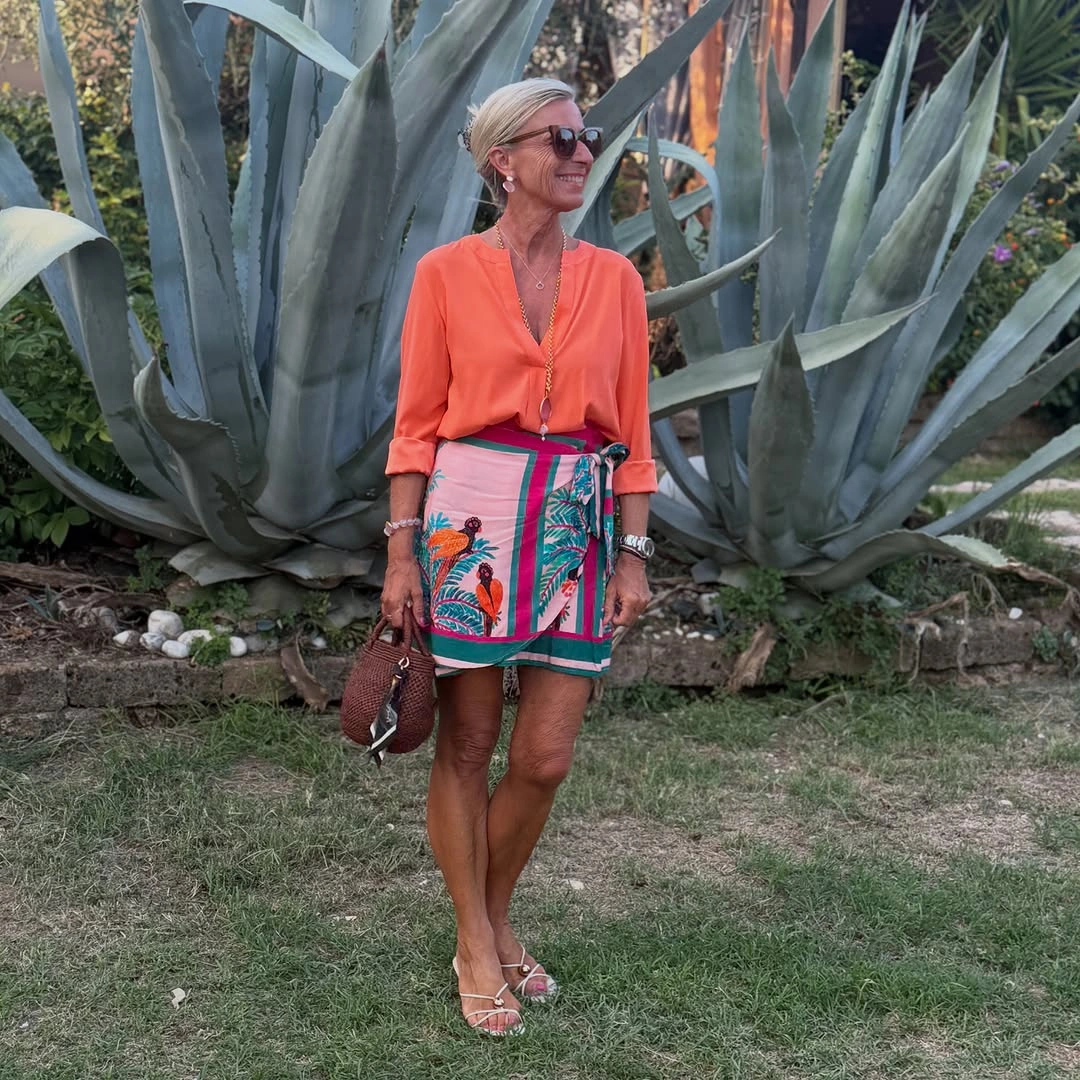Coral blouse with colorful wrap skirt and white sandals