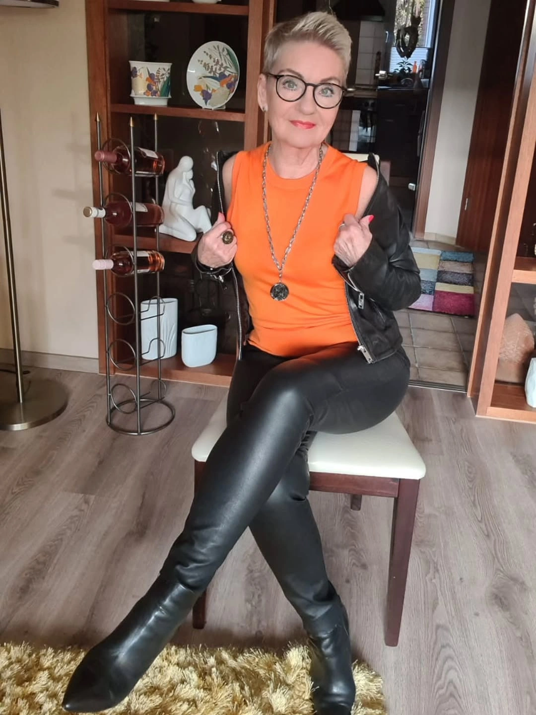 Orange sleeveless top with black jacket and tall boots