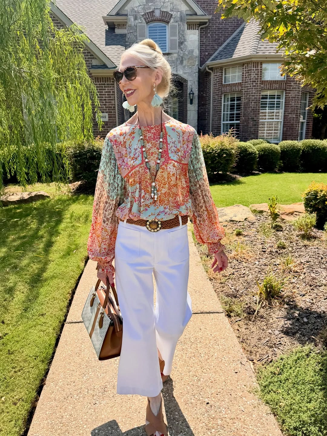 Multicolor floral blouse with cropped white trousers and tan bag