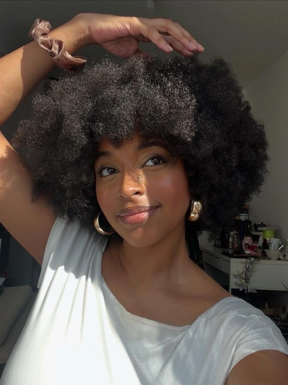 Full rounded afro with soft bangs and hoop earrings