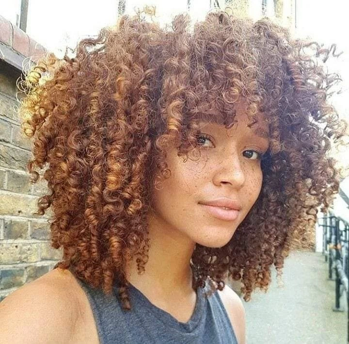 Copper shoulder-length curls with full bangs and dark top