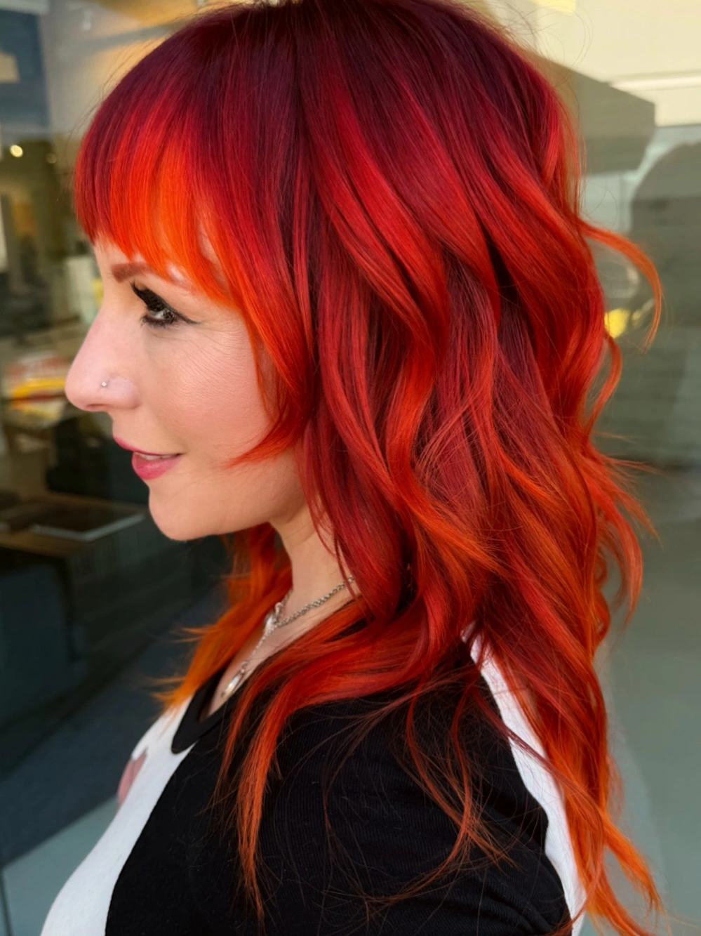 Layered red-orange waves with full bangs and black top