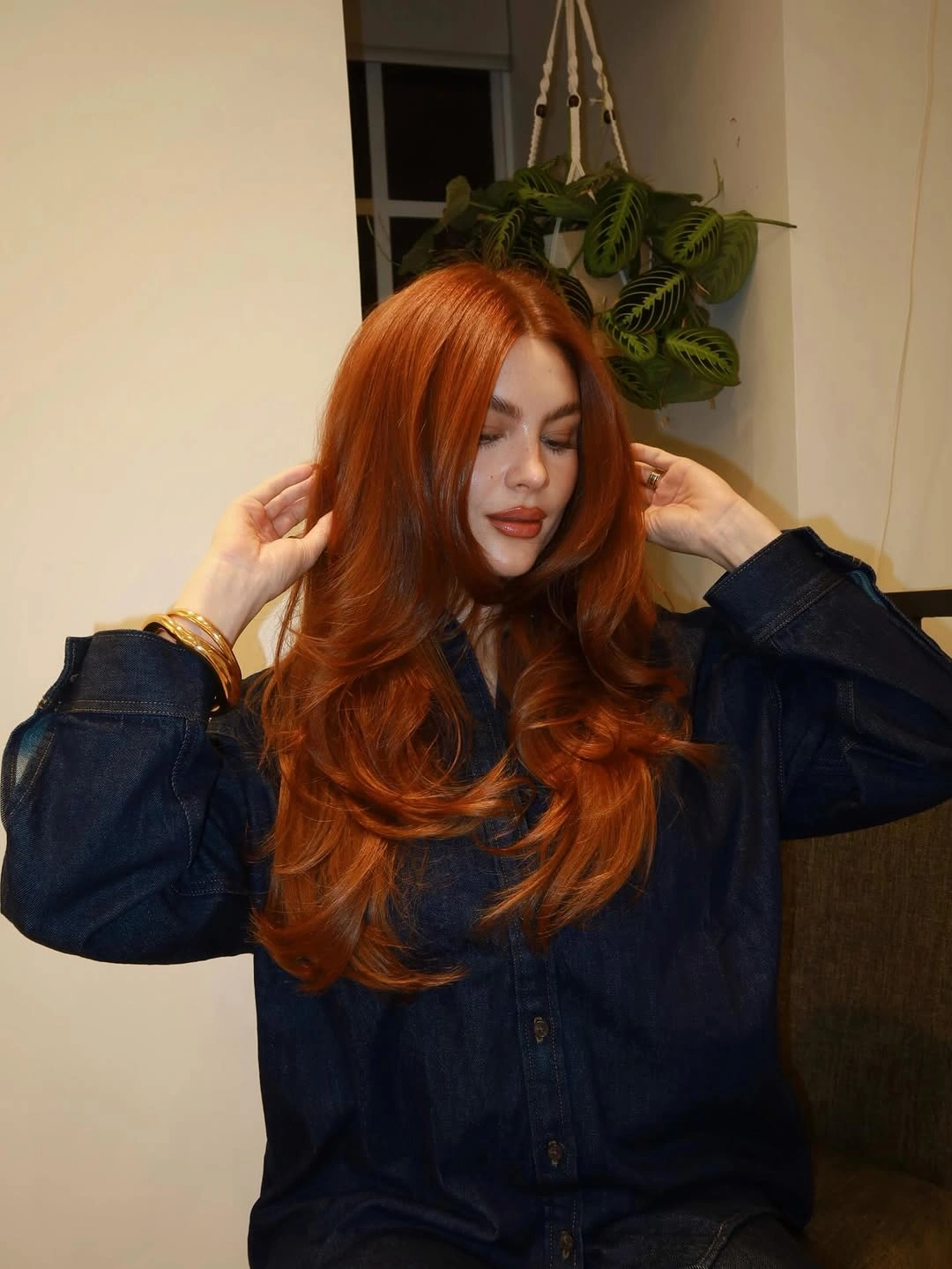 Long copper-orange layered hair with dark button-front shirt