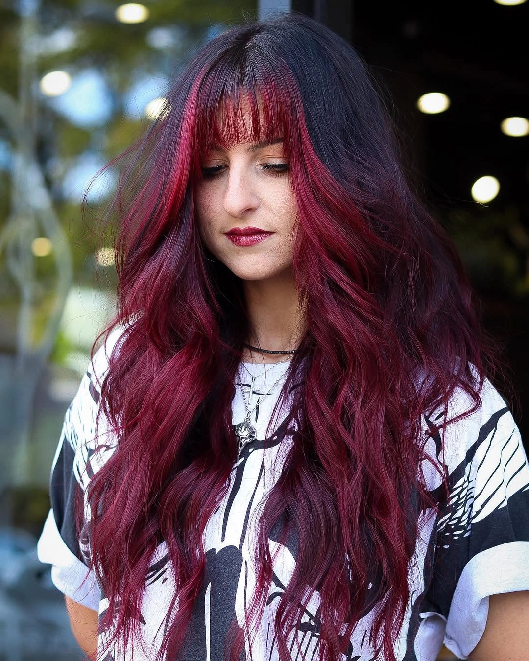 Long wine-red wavy hair with full bangs and graphic shirt