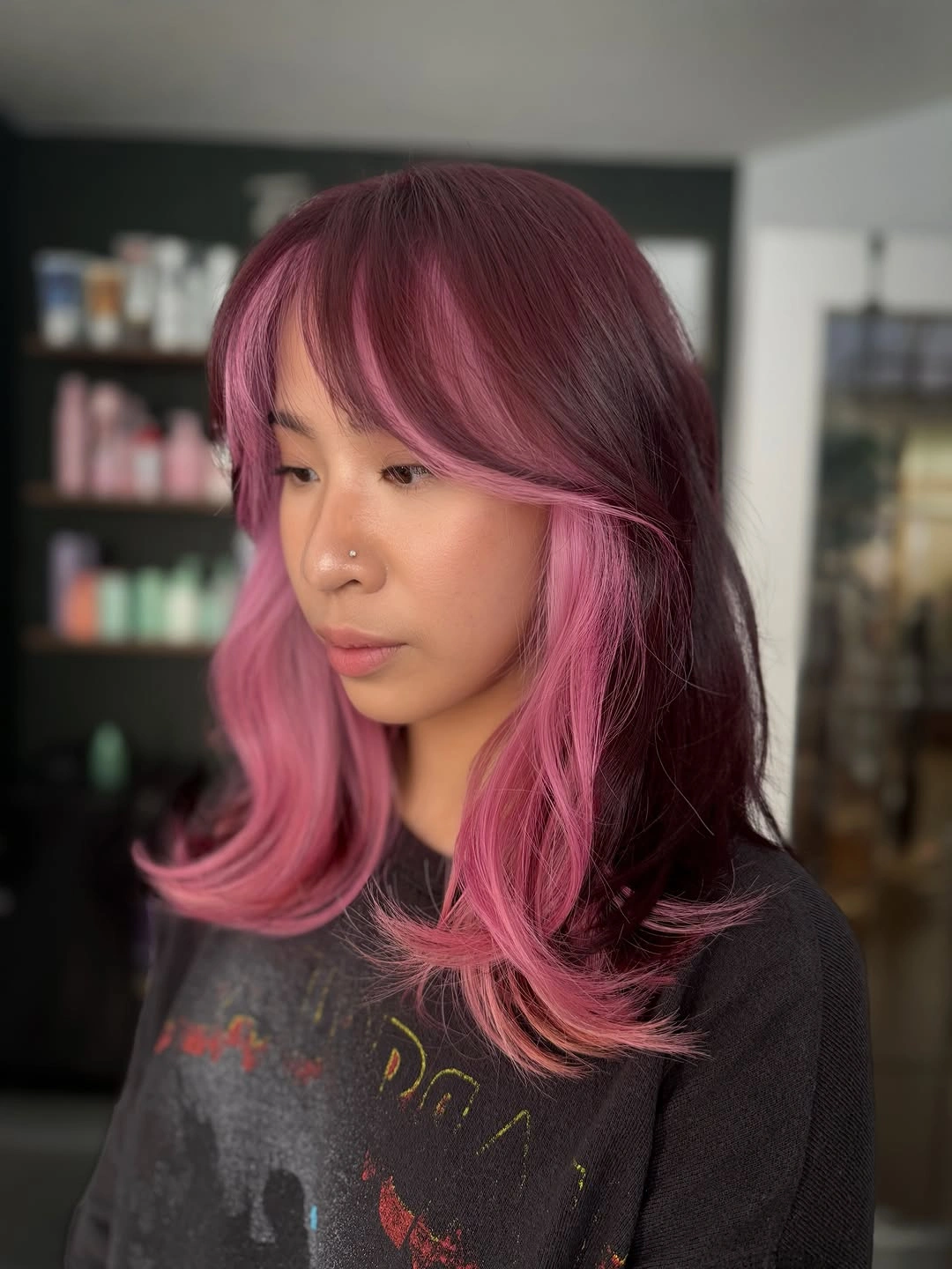 Shoulder-length plum and pink layered hair with side-swept bangs