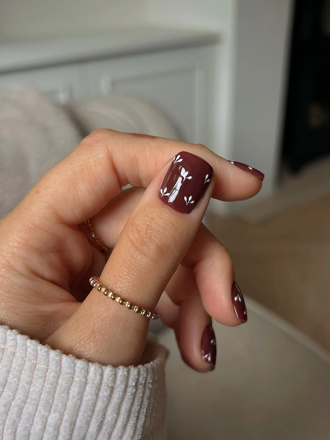 Burgundy short nails with small white sprig accents