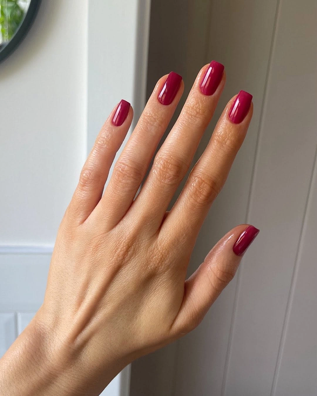 Glossy berry tapered nails beside pale wall