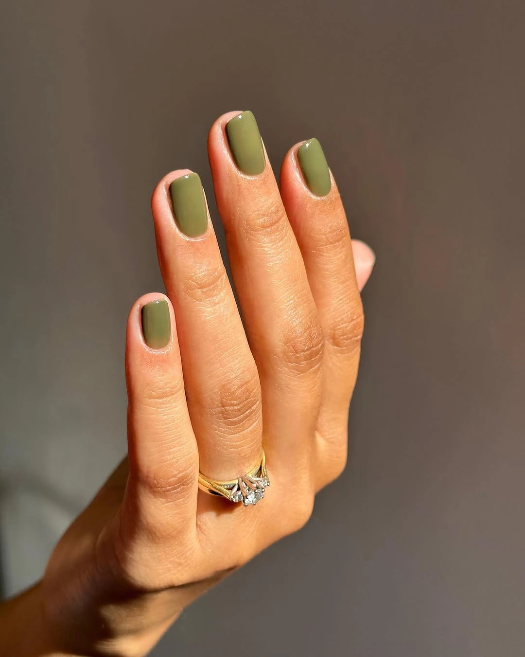 Muted olive short square nails in warm sunlight