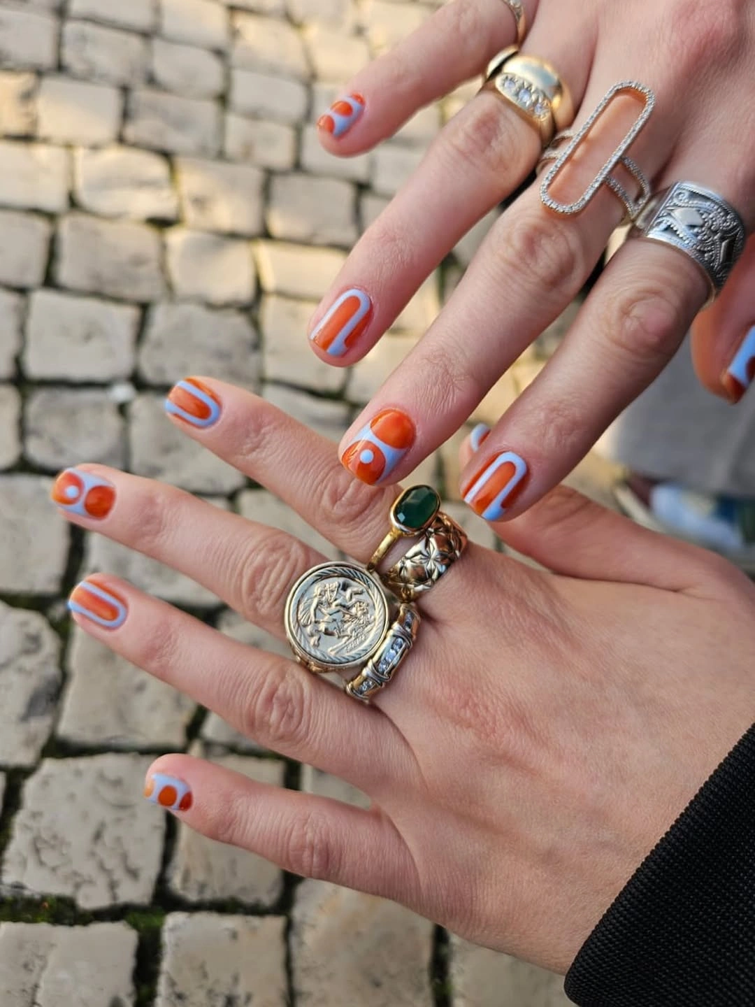 Orange and pale blue graphic short nails with rings