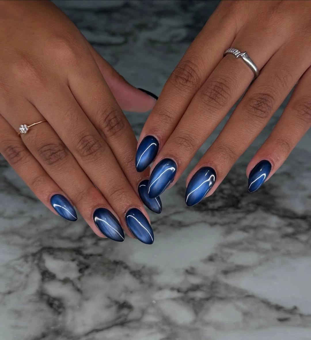Deep magnetic blue almond nails on brown hands
