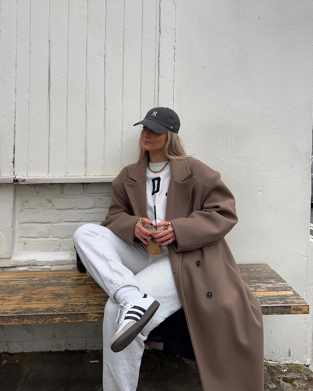 Taupe oversized coat with gray joggers, sweatshirt and striped sneakers