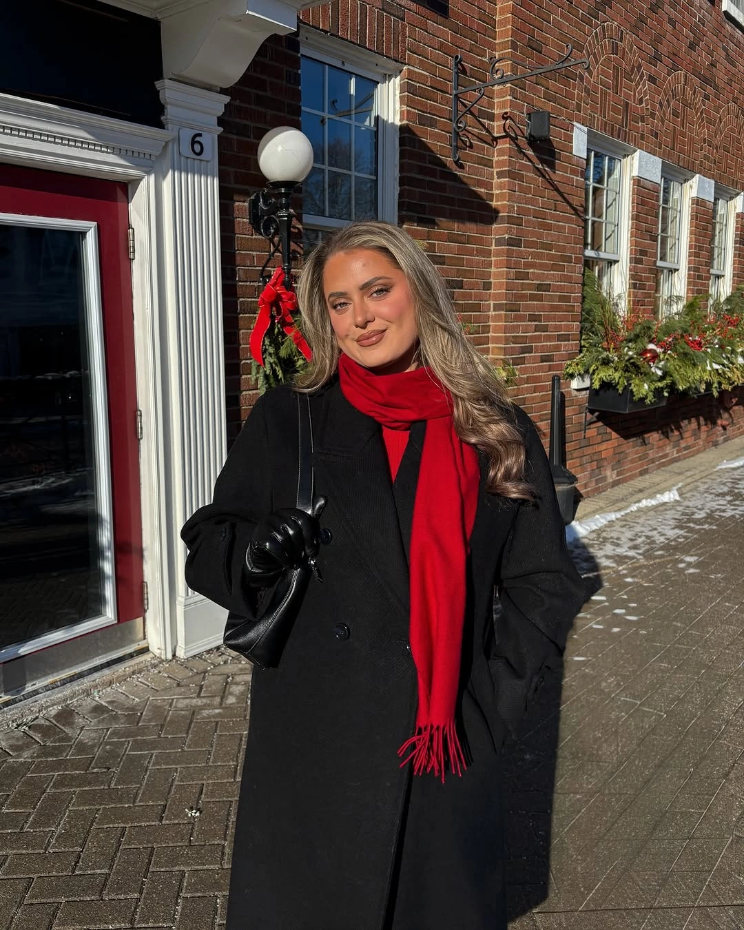 Black winter coat with long red scarf and black gloves