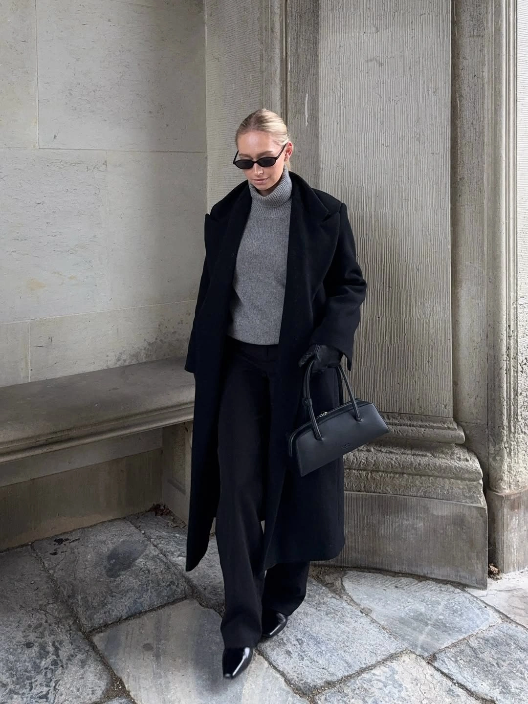 Black coat with gray ribbed turtleneck and wide trousers