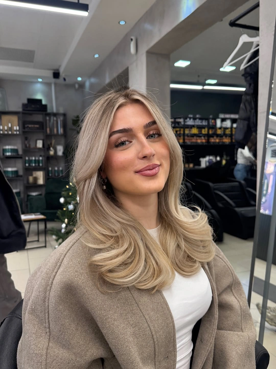 Rooted beige blonde hair with rounded face-framing layers