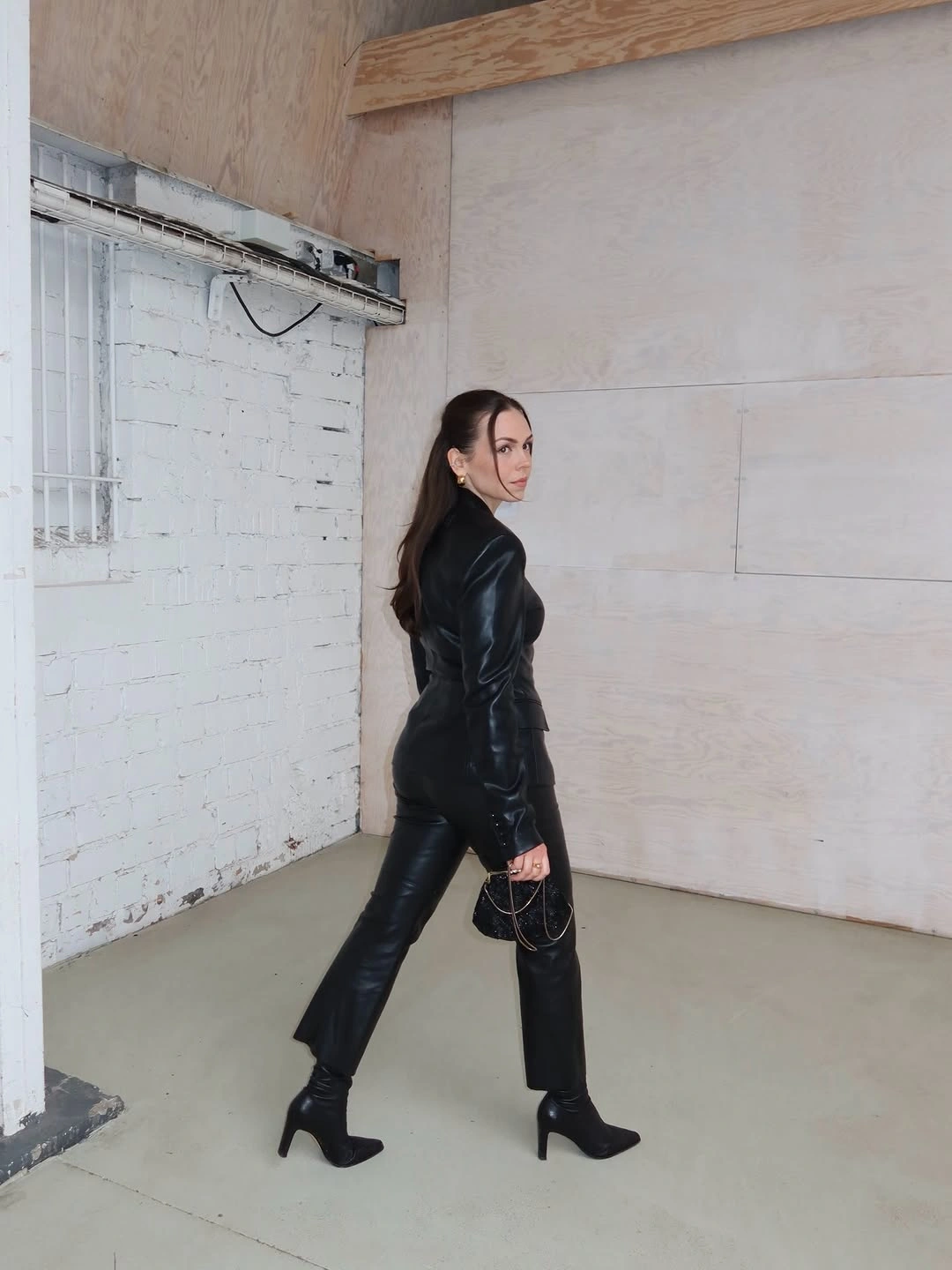 All-black glossy outfit with heeled ankle boots and chain bag