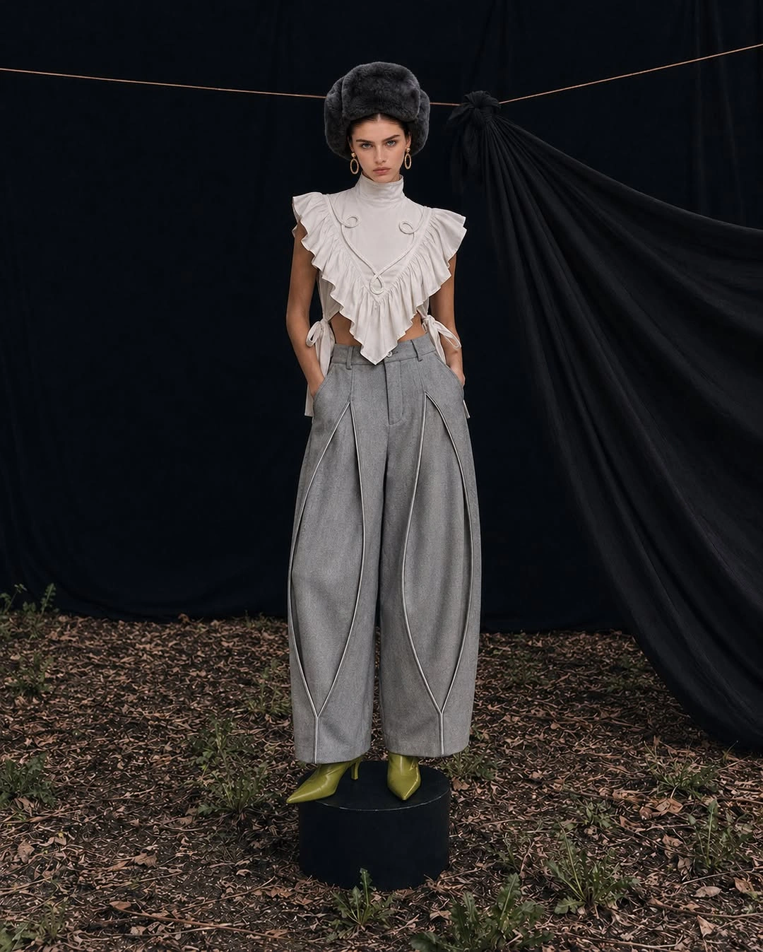 Gray barrel trousers with white ruffled top and green pointed shoes