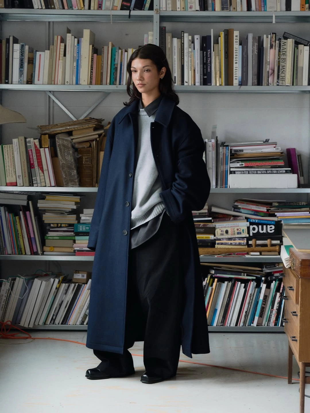 Long navy coat with gray sweater and wide black trousers