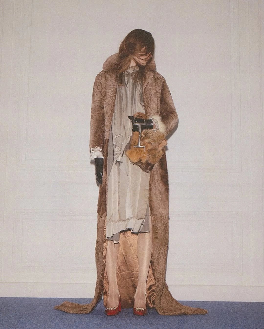 Brown textured coat over pale layers with red pointed shoes