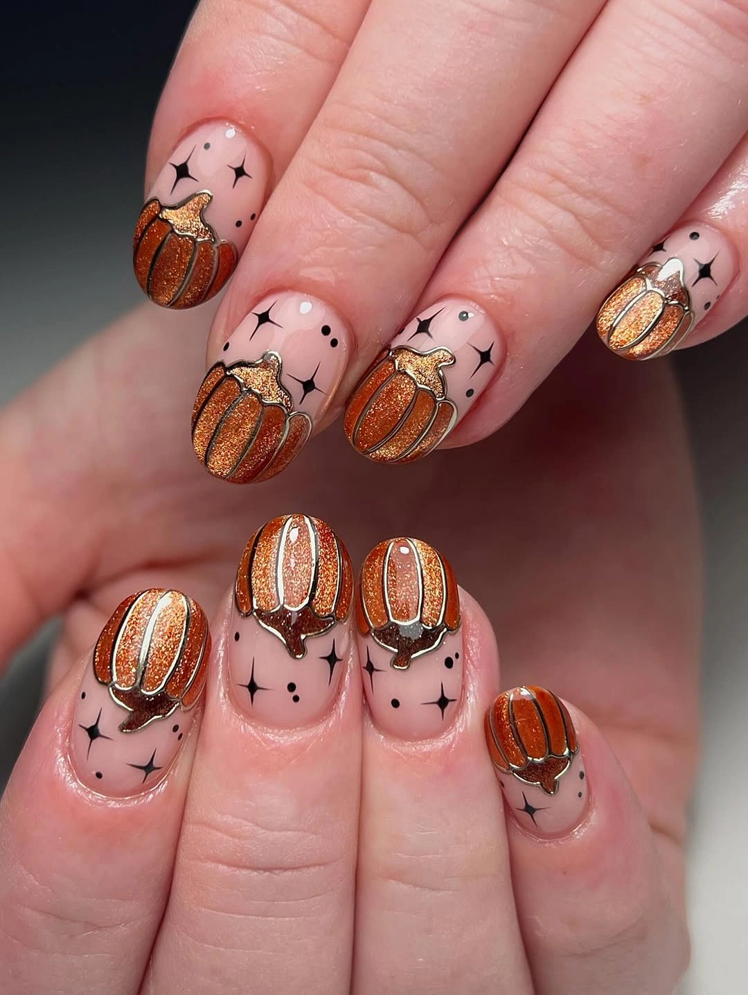 Pale pink nails with repeated orange pumpkin details