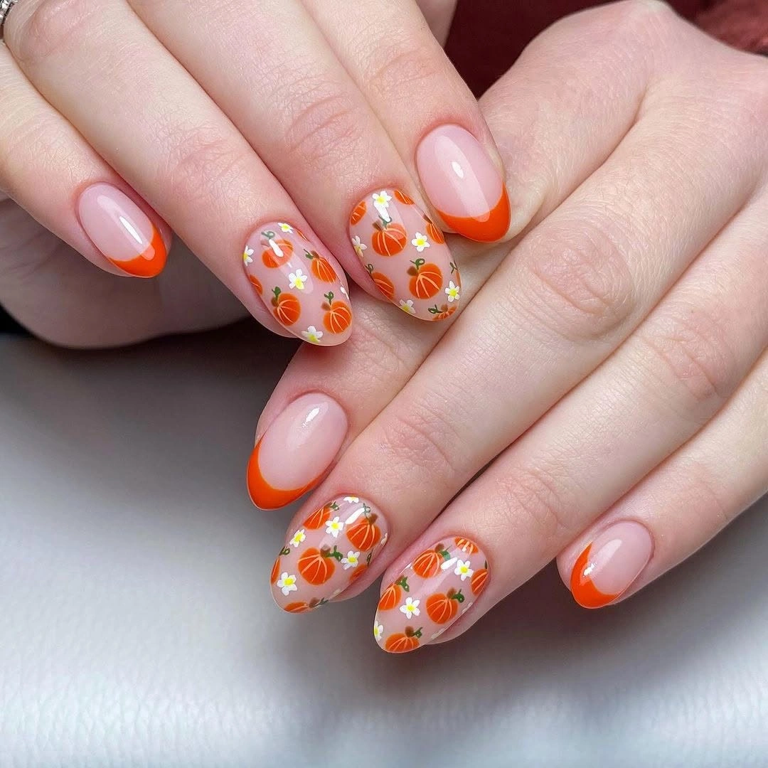 Sheer pink nails with orange pumpkin French-like tips