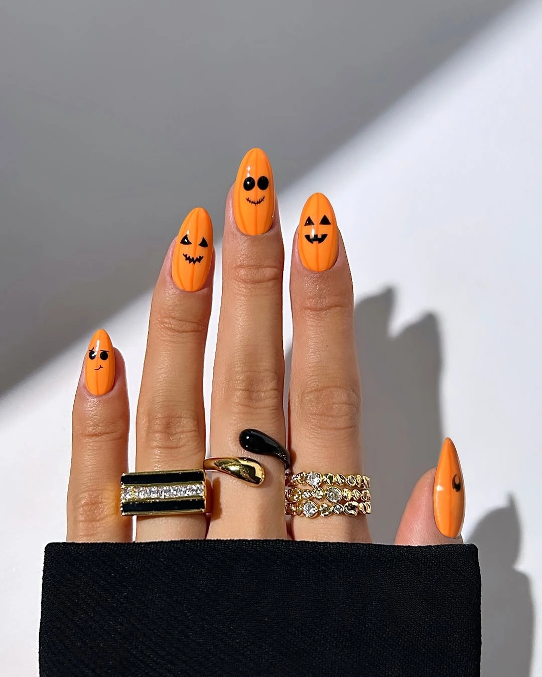Bright orange nails with bold black pumpkin faces