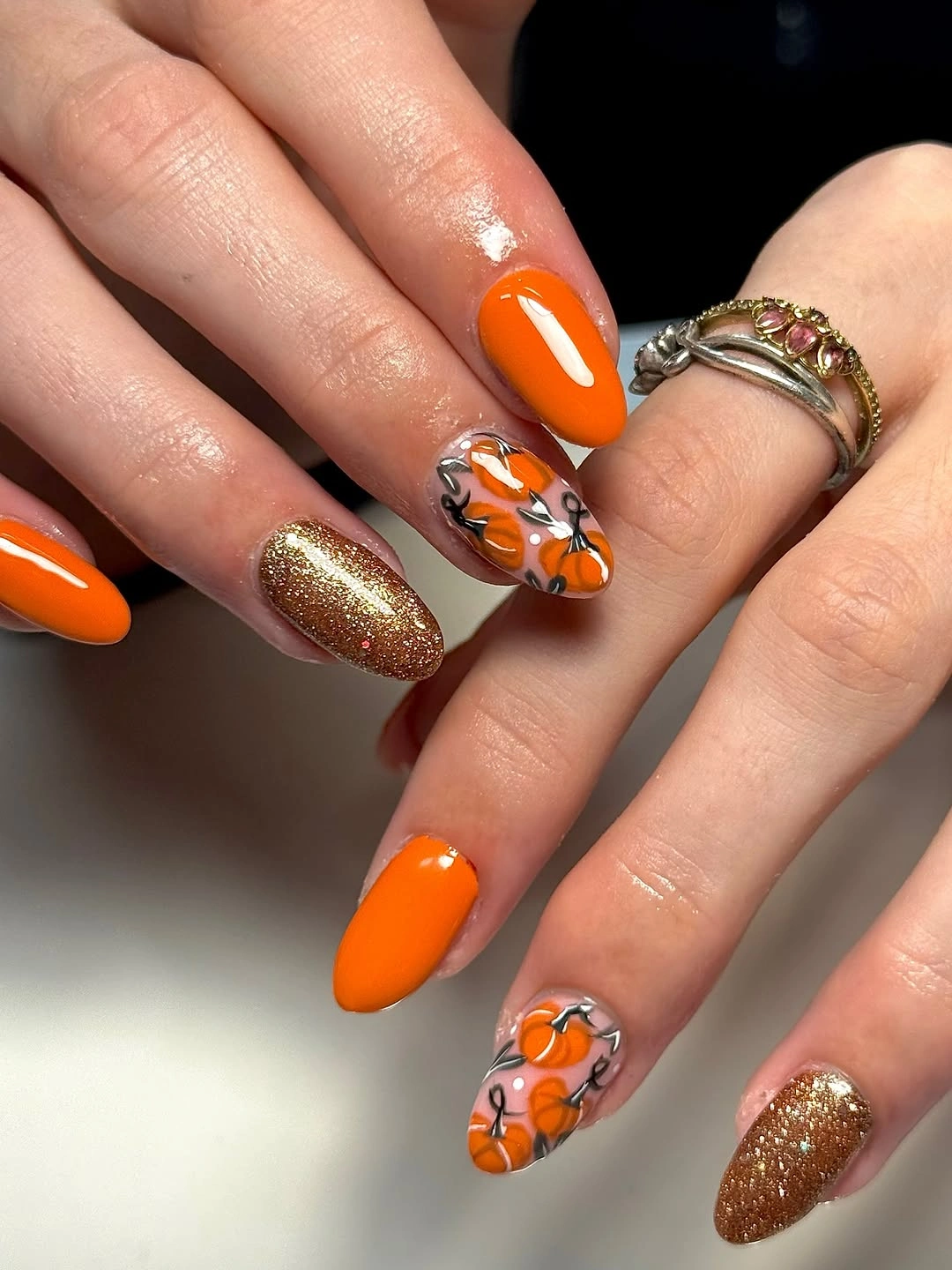 Orange almond nails with gold glitter and pumpkin art