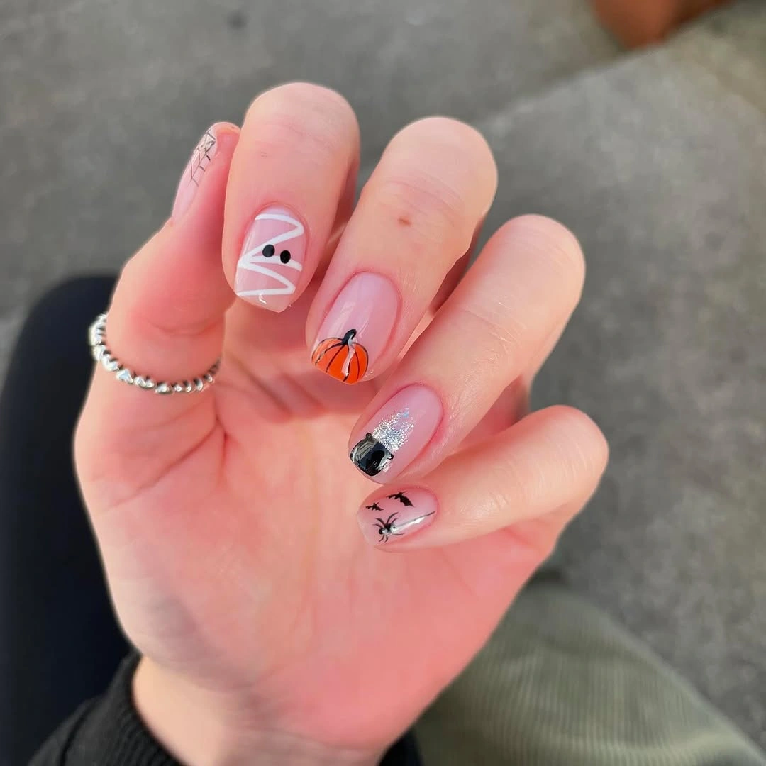 Short pink orange nails with tiny pumpkin accents