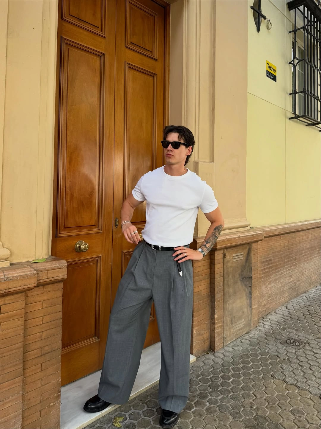 Man in white tee, pleated gray trousers and black shoes