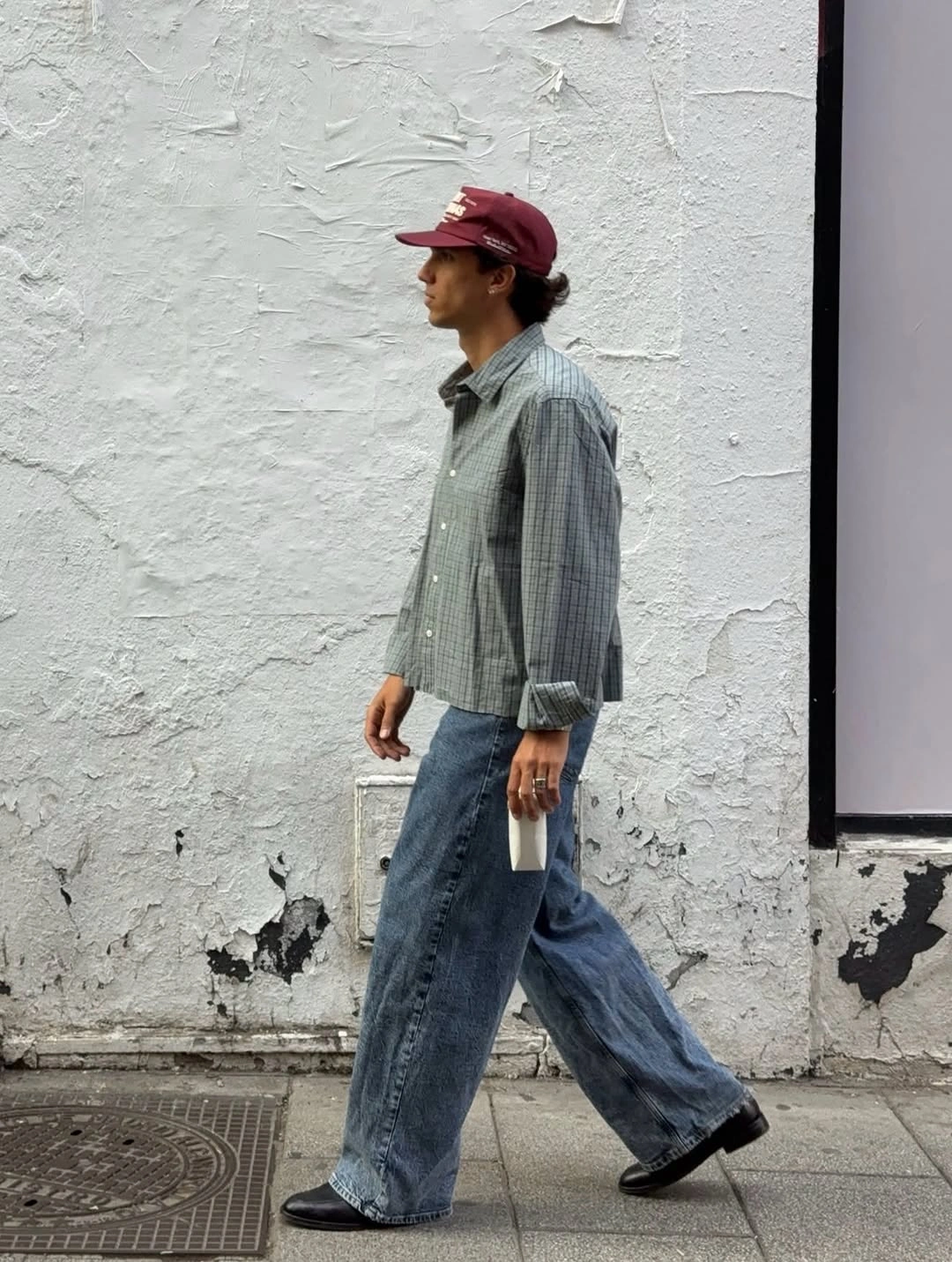 Man in micro-check shirt, burgundy cap and wide jeans