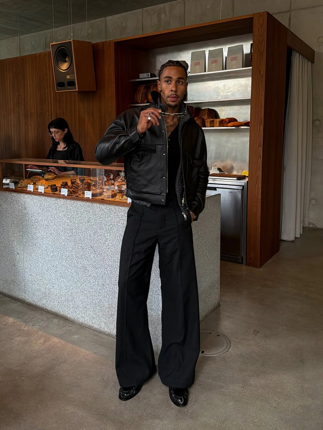Man in black leather-look jacket, wide trousers and silver necklaces