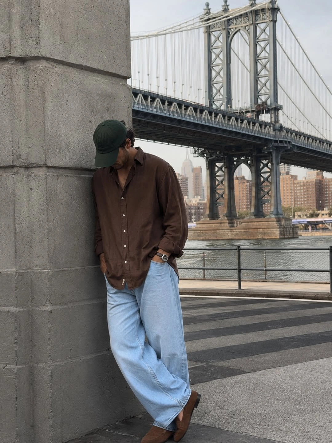 Man in brown open shirt, olive cap and pale wide jeans