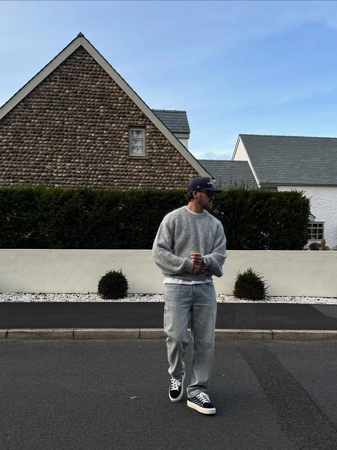 Man in soft gray sweater, pale jeans and black sneakers
