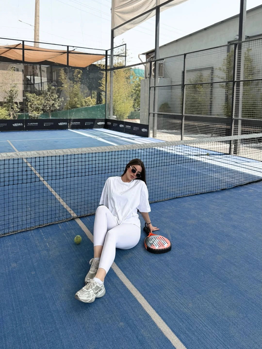 Oversized white tee and long white legwear on blue padel court