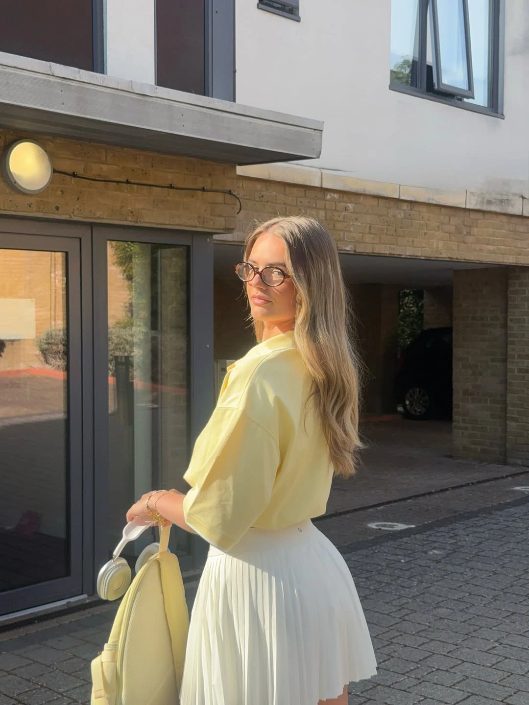 Pale yellow top with white pleated skirt and racket bag