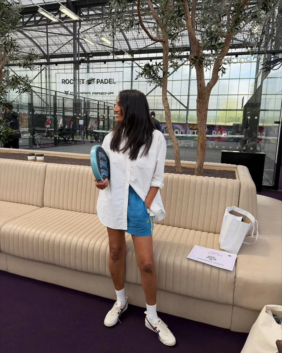 Open white button-down with blue shorts in padel lounge