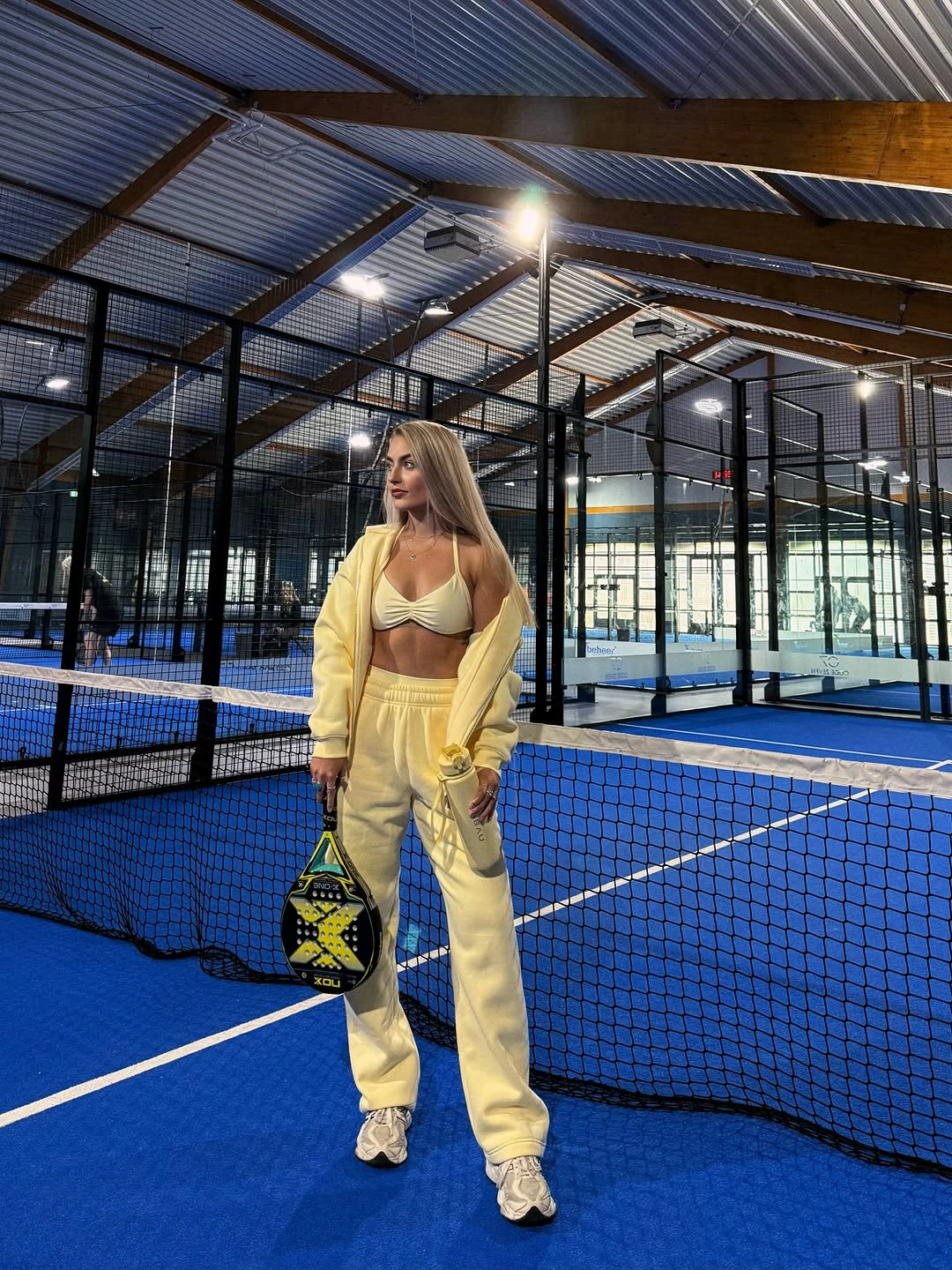 Pale yellow layered outfit with wide pants and black racket