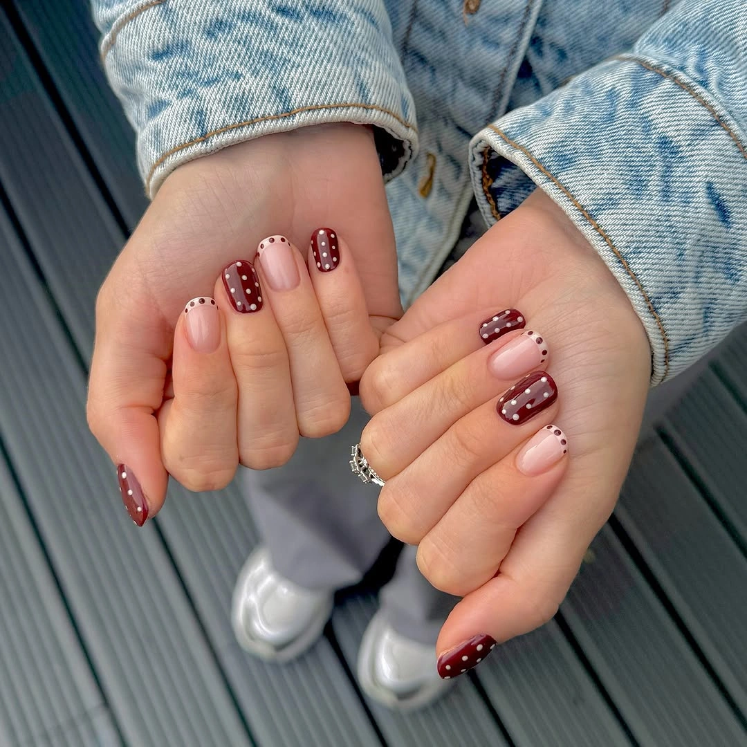 Short burgundy and pink rounded nails with white dotted accents