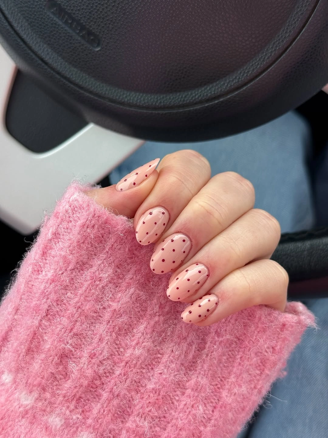 Sheer pink almond nails covered with small burgundy dots