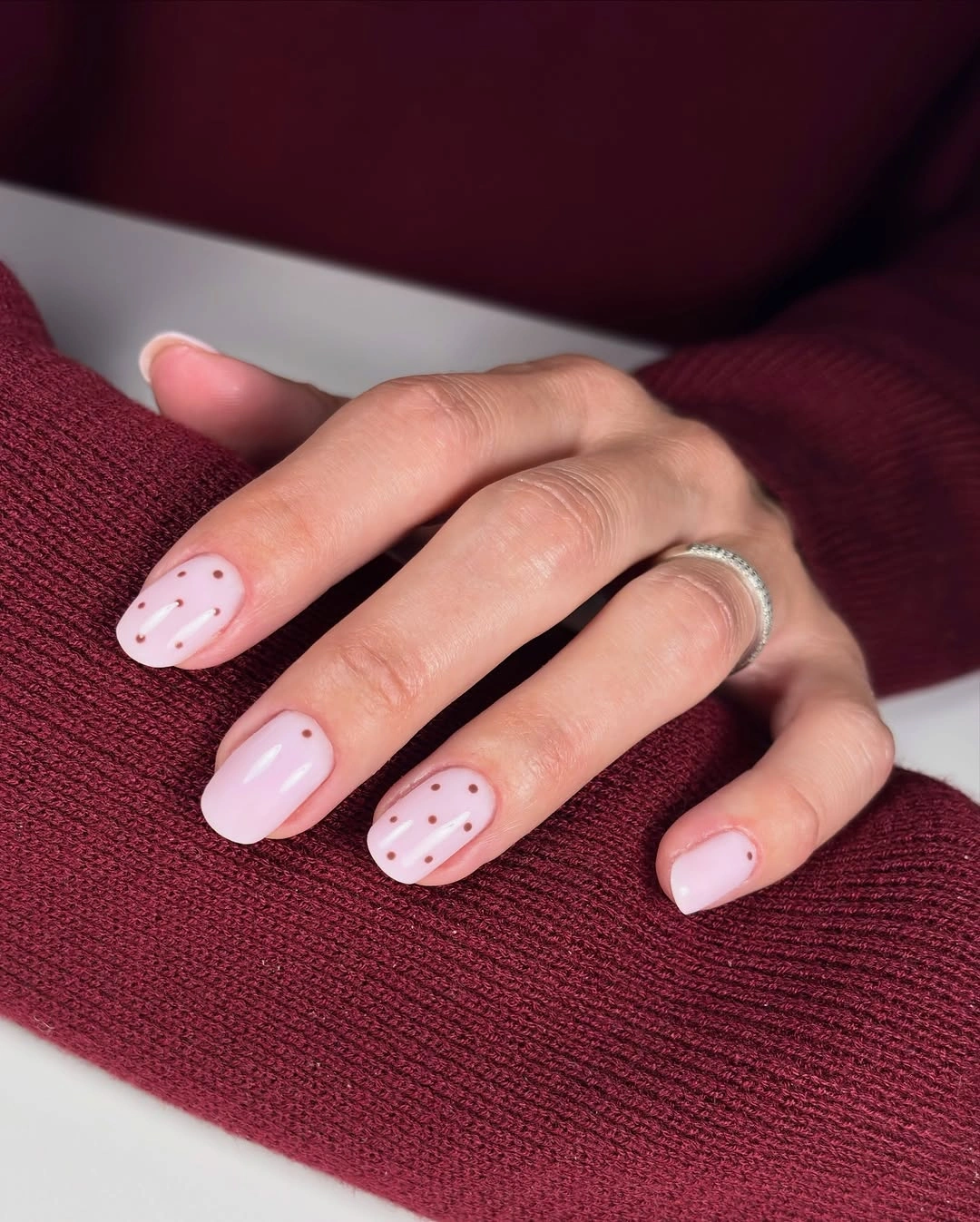 Short blush pink nails with delicate white polka dots