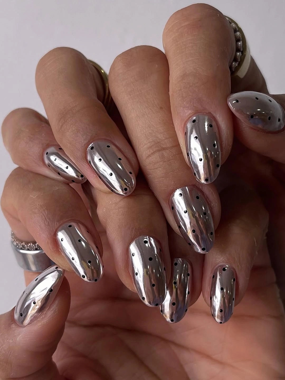 Reflective silver almond nails with scattered black dots