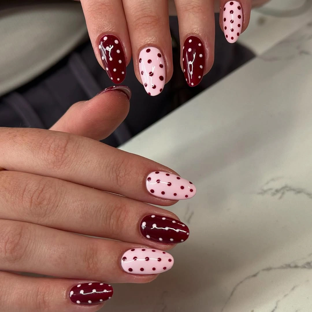 Burgundy and pink almond nails with dots and white curves