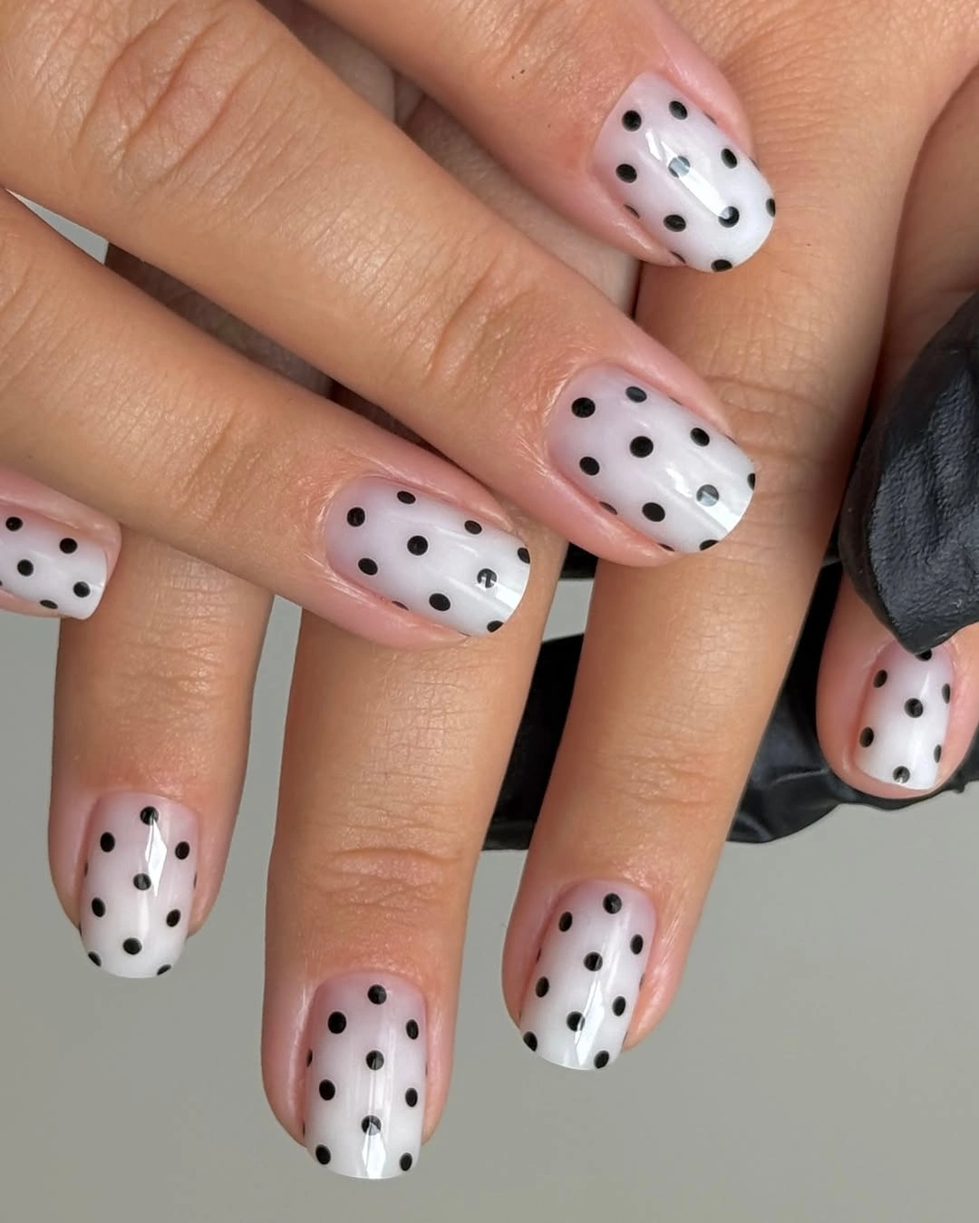 Rounded white nails with bold black polka dots