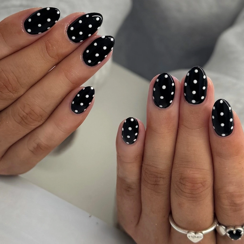 Glossy black almond nails with evenly spaced white dots
