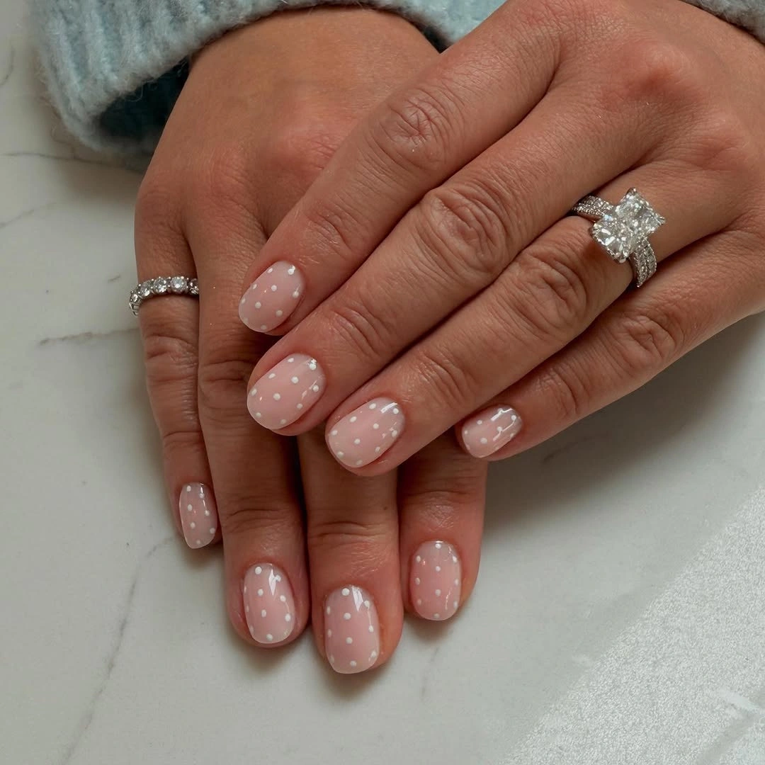 Short rounded pink nails with tiny white dots