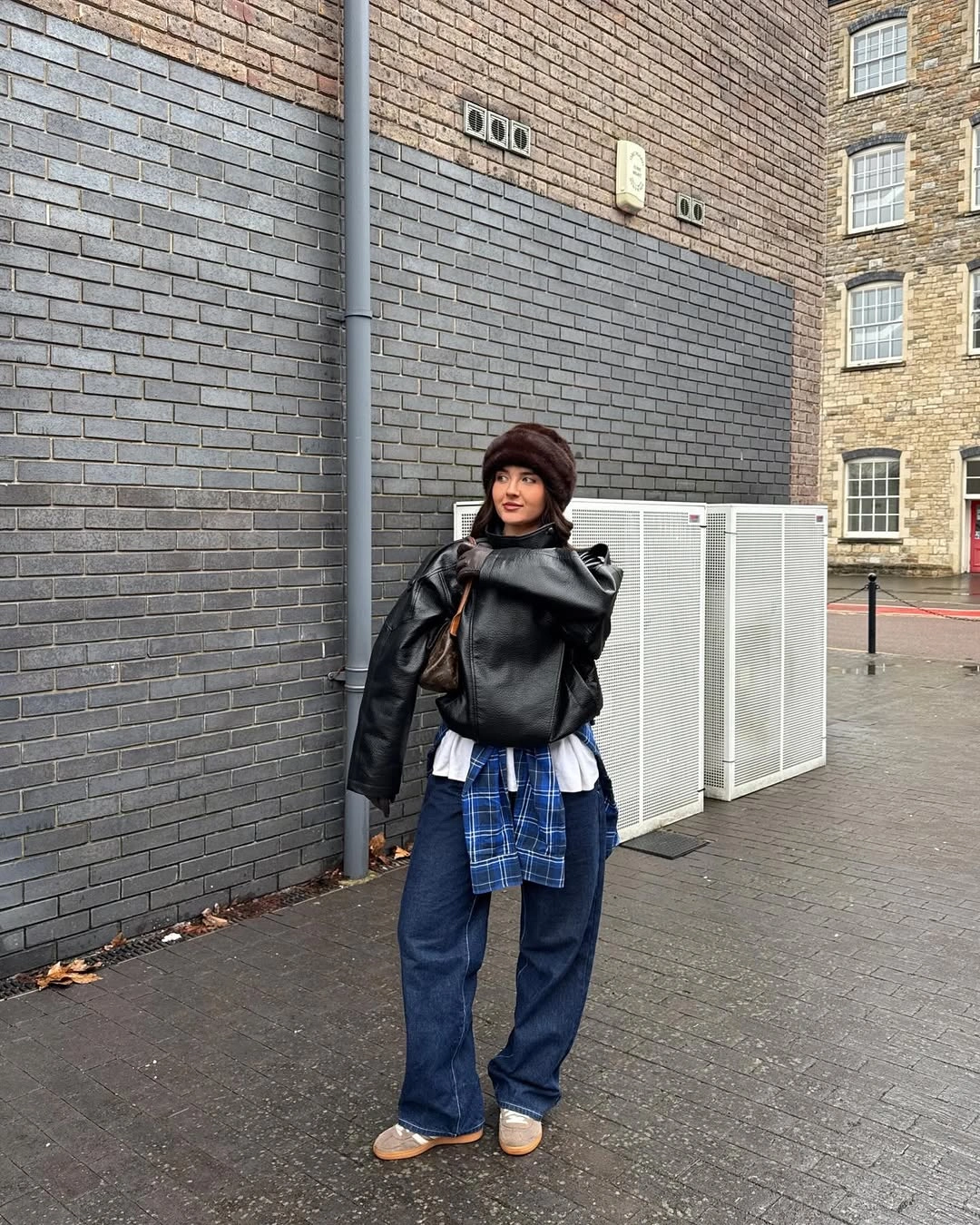 Black jacket with tied plaid shirt and wide blue jeans