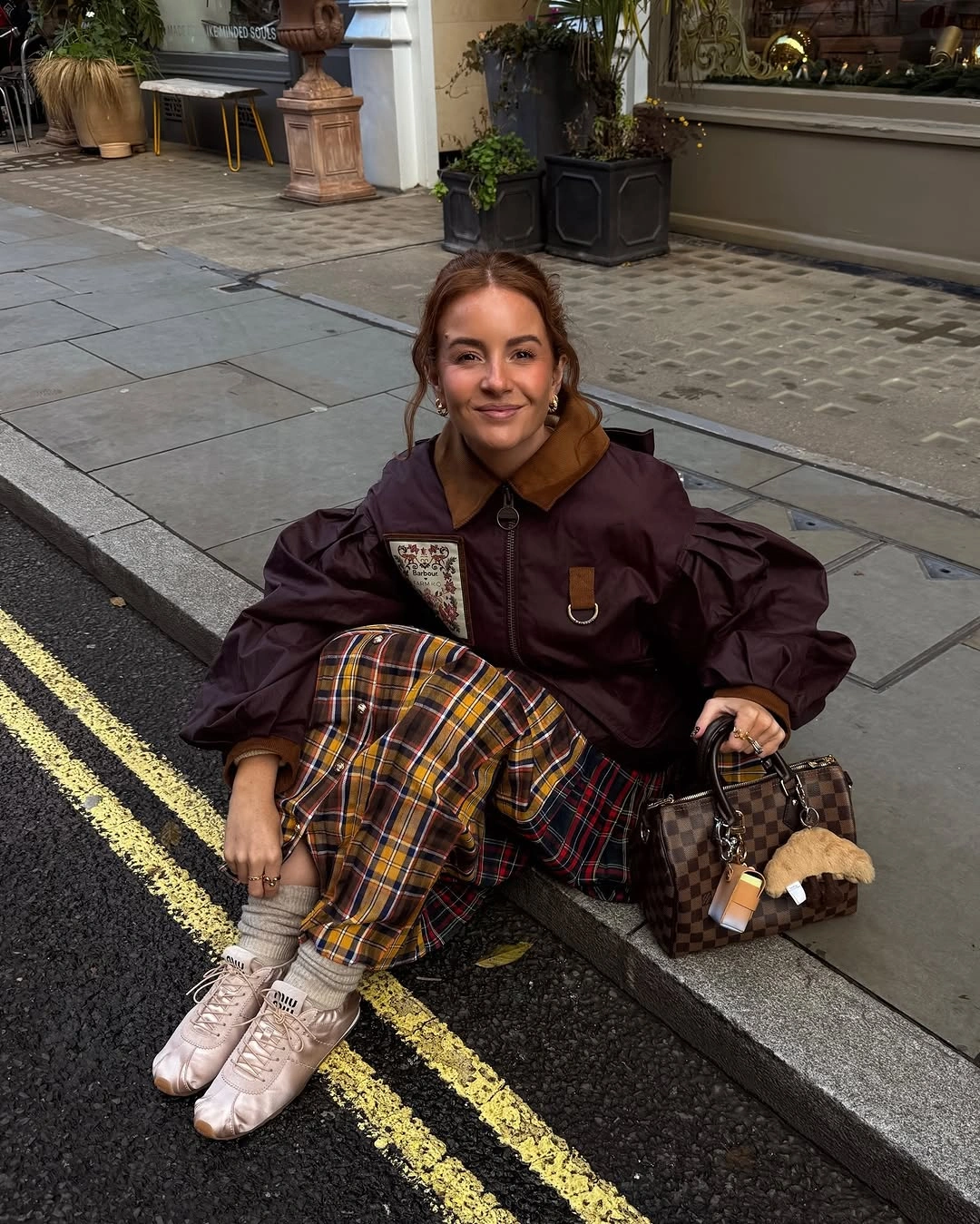 Burgundy jacket with large plaid lower layer and pale sneakers